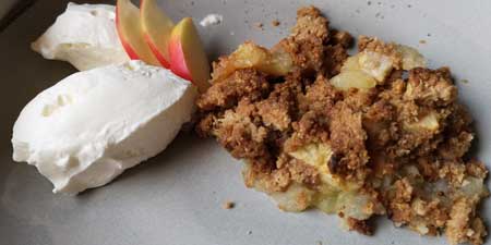 Warm apple crumble with vanilla ice cream and whipped cream
